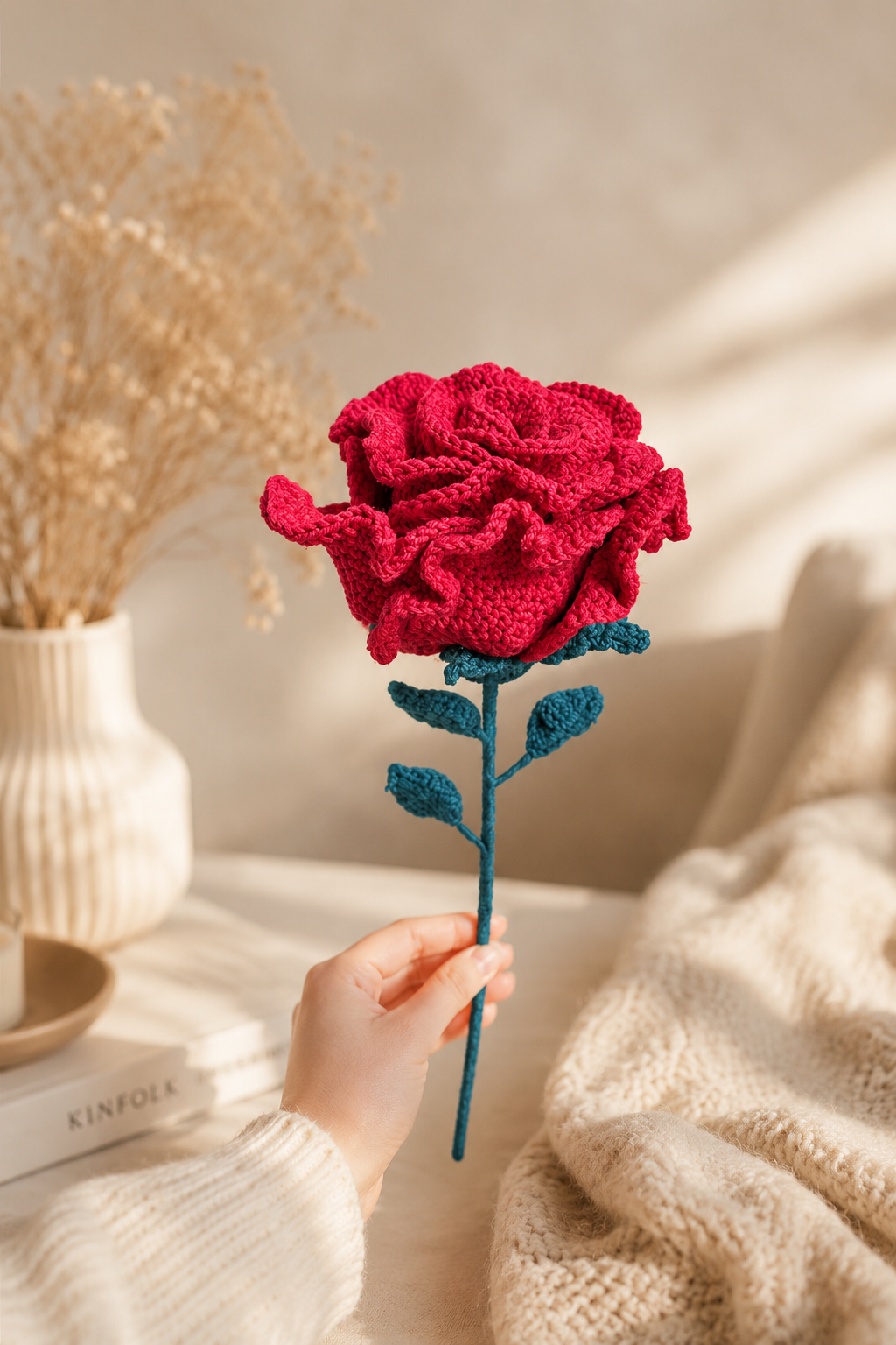 Hand holding a hand-knitted crochet red rose